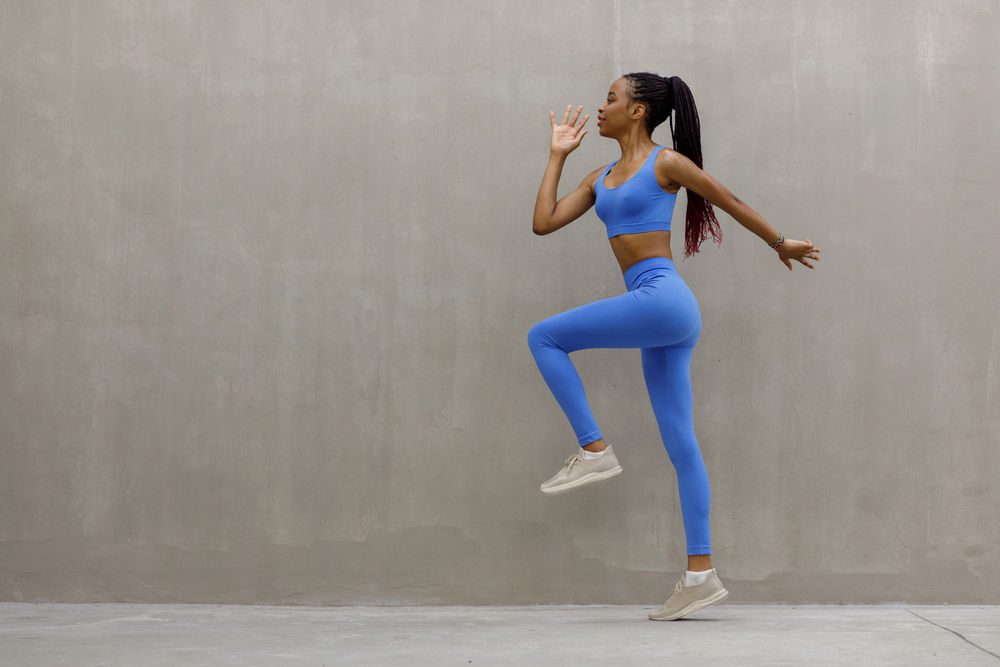 Jeune femme réalisant des montée de genoux pour s'échauffer avant le sport